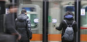 Транспорт в Корее. Пассажиры в зимней одежде ждут поезд за стеклянными дверями платформы