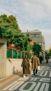 Пара в длинных пальто гуляет по улице в Сеуле осенью