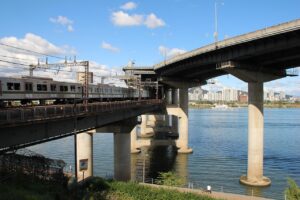 Сеульский поезд метро пересекает мост через реку Ханган на фоне городских небоскрёбов