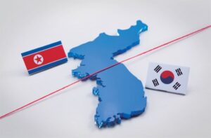 Карта Корейского полуострова с флагами КНДР и Республики Корея, разделённая красной линией.