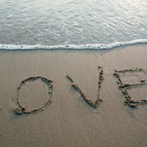 Слово "LOVE", написанное на песке у края моря.